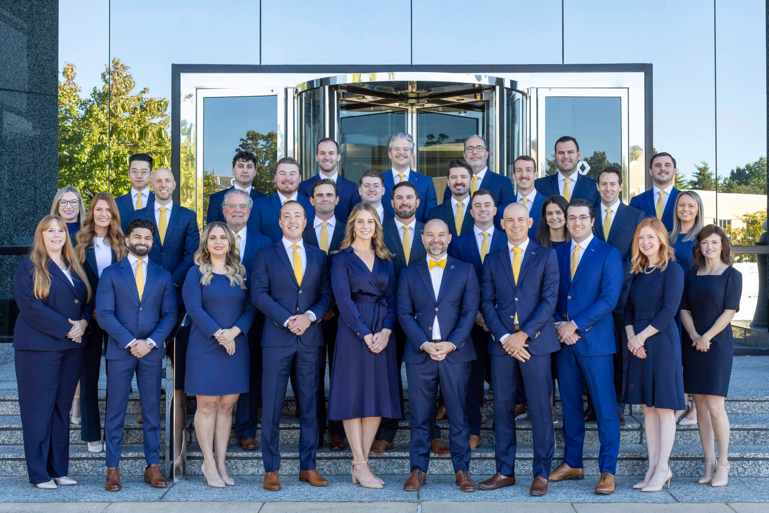 Gatewood's entire team in navy blue suits and dresses standing outside.